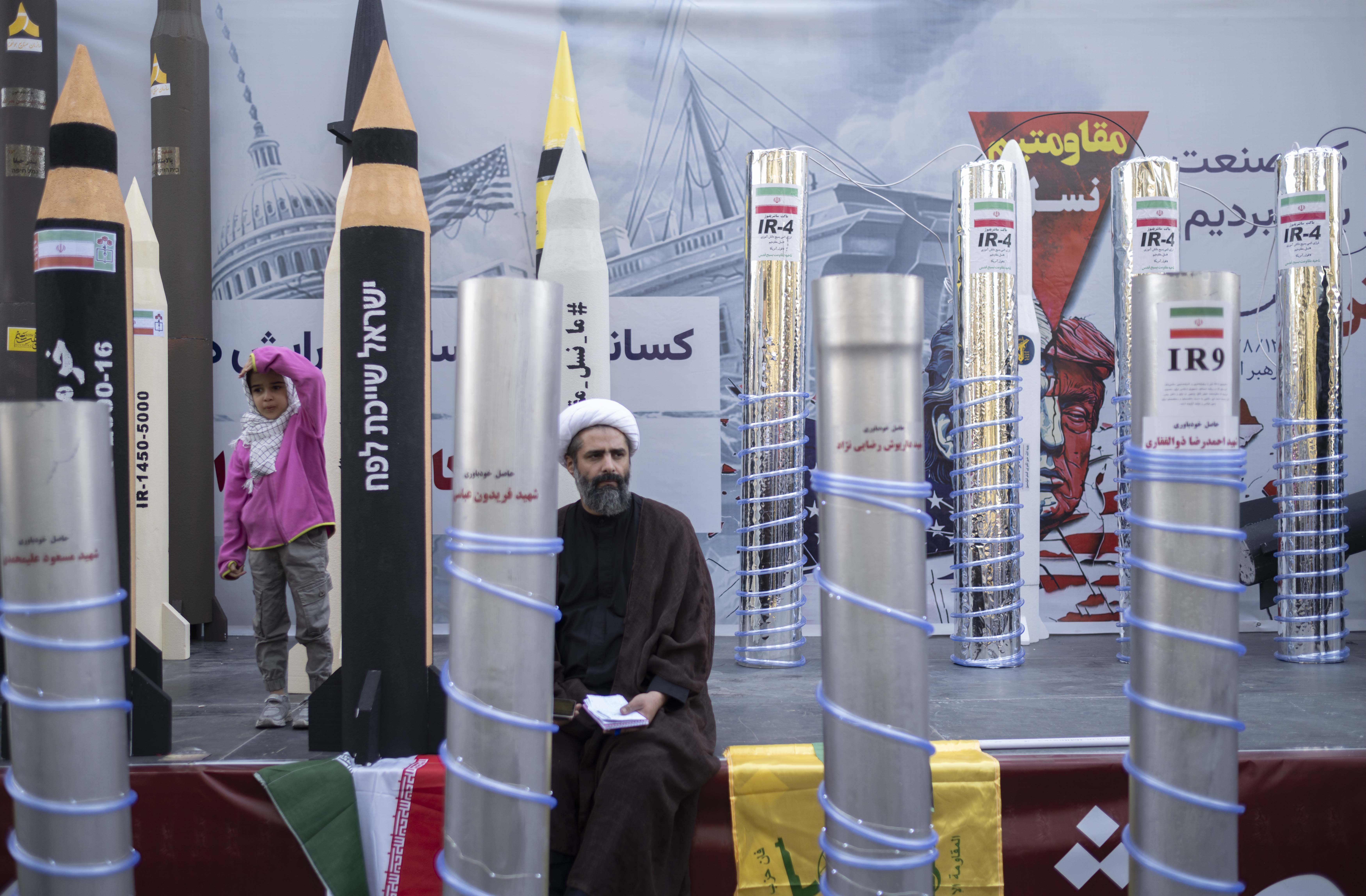 A cleric stands in front of a display of Iranian missiles